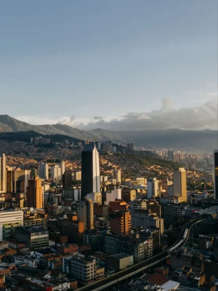 Aerial view of Medellín, Colombia at sunset, with the city skyline and surrounding mountains